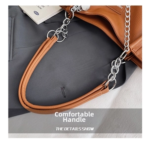 Close-up of caramel brown tote bag with leather handles and silver metal chain detail