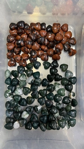 Macro shot of 15mm heart-shaped natural crystal stones in a clear storage box