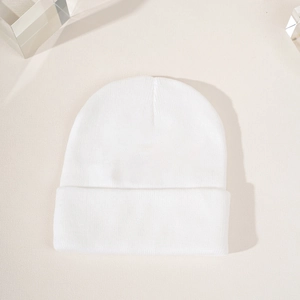 Mise à plat d'un bonnet en tricot blanc avec revers large sur fond minimaliste texturé