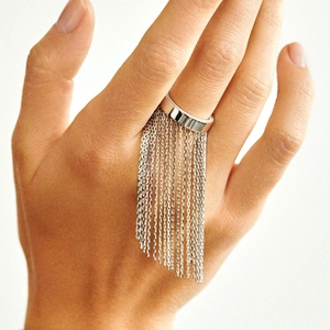 Close-up of wide silver stainless steel ring featuring long delicate chain tassels