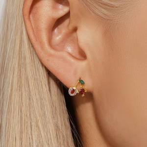 Close-up of cherry stud earrings with red and orange gemstones on golden metal