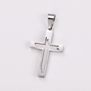 Macro shot of silver stainless steel cross pendant featuring engraved Lord's Prayer text