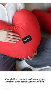Close-up of a large red heart-shaped pillow with soft texture and Happy Home label