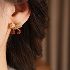 Gros plan de boucles d'oreilles cerise avec cristaux portées par un mannequin chic