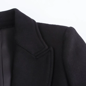 Macro view of black wool coat lapel showing high-quality stitching and fabric texture