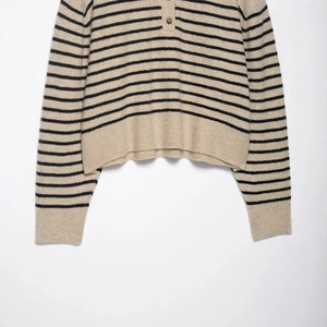 Pull rayé en tricot avoine et noir avec une coupe courte et des boutons au col