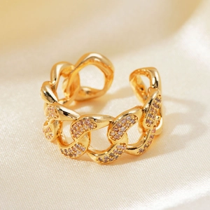 Macro shot of a gold chain link ring with pink micro-inlaid zircons on silk fabric