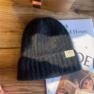 Detail of grey gradient knitted beanie with 1982 California tag on wooden background