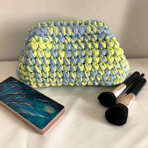 Macro detail of hand-woven crochet clutch bag in light blue and yellow chunky knit yarn