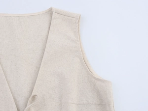 Dettaglio dello scollo a V e della trama in misto lino di un gilet beige senza maniche