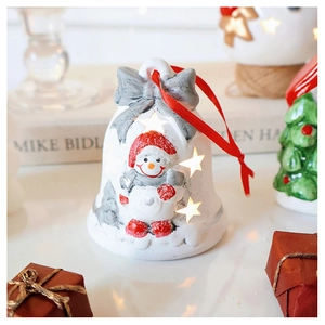 Close-up of white star-hollowed ceramic bell ornament with warm LED light and red snowman
