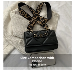 Detailed view of black quilted crossbody bag featuring chain and patterned strap with phone scale