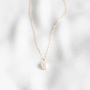 Minimalist freshwater pearl necklace in 14K gold plating on soft white silk fabric