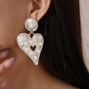 Gros plan de grandes boucles d'oreilles cœur argentées avec cristaux sur un mannequin