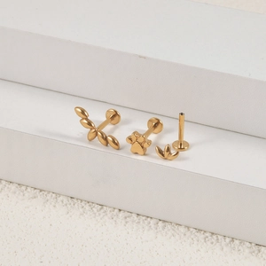 Detailansicht vergoldeter Labret-Stecker mit Blatt- und Pfotenmotiven für Piercings