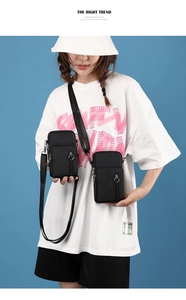 Detail of small black crossbody phone bag with heart-shaped zipper and adjustable strap