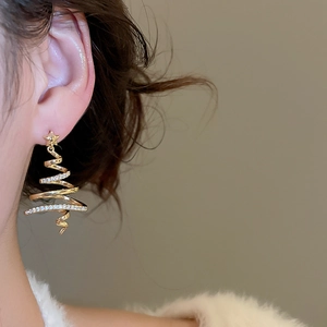 Detail of gold-plated Christmas tree earring with glittering zircons worn on ear