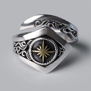 Macro shot of retro steel ring featuring wave relief and golden compass star on black base