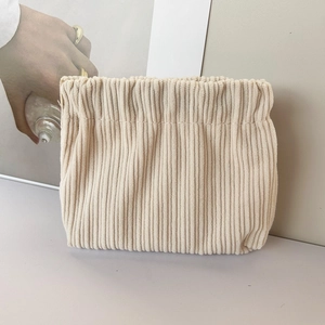 Detail of beige corduroy storage bag showing vertical texture and squeeze closure