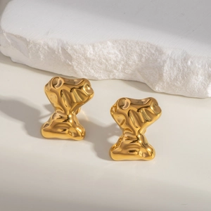 Makroaufnahme minimalistischer goldener unregelmäßiger Ohrringe mit polierter Textur