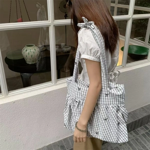 Detail of checkered tote bag with bow prints and pleated drawstring design on the side