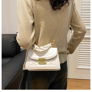 Detalle de bolso bandolera blanco acolchado con cierre metálico dorado y asa de cadena