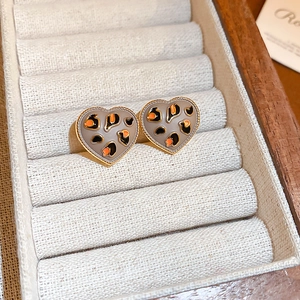 Détail de boucles d'oreilles cœur à motif léopard avec bordure dorée dans une boîte