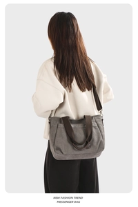 Detail of grey canvas crossbody bag with dark brown webbing straps worn by model