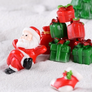 Miniature Christmas resin figurines with Santa Claus and gift boxes on snow