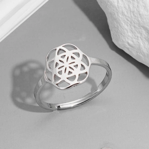 Detailed view of silver flower of life ring on a white textured stone and grey backdrop