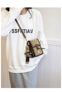 Detail of vintage canvas crossbody phone bag with brown leather trim and rabbit charm