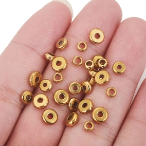 Macro view of gold stainless steel wheel beads and spacer beads held in hand for DIY jewelry