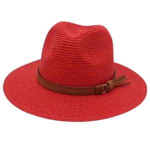 Detail of red fedora hat featuring woven texture and brown leather belt with metal buckle