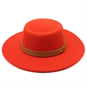 Detail of red wool felt boater hat with a brown leather strap and gold metal buckle