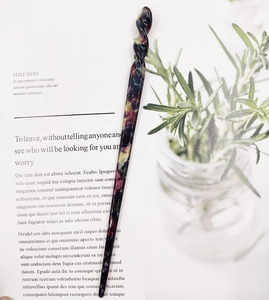 Close-up of spiral acetate hair stick with purple and yellow tortoiseshell pattern