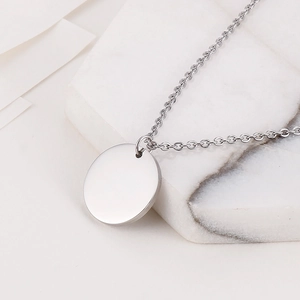 Vue macro d'un collier avec pendentif disque rond argenté poli sur marbre