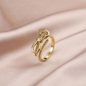 Macro detail of gold bow ring with sparkling pavé zircons on elegant silk fabric
