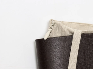 Gros plan détaillé des coutures en cuir marron et toile beige sur le sac à main chic