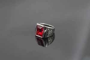 Macro detail of vintage silver steel ring featuring rectangular red gemstone and leaf carvings
