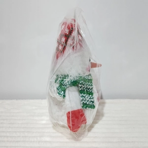 Detail of a Christmas plush snowman ornament with red hat and green scarf decor