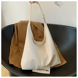Close-up of a large beige tote bag in high-quality leather being held by a hand