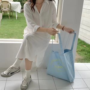Detail of light blue canvas tote bag with yellow PARIS embroidery and floral lettering