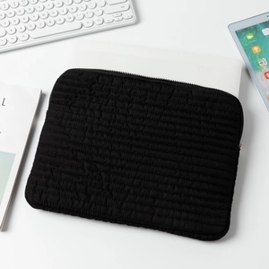 Detailed view of the black quilted laptop sleeve with horizontal padded stitch and metal zipper