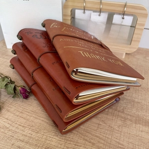 Vintage A6 PU leather notebooks in brown with customized gold foil text on wooden table