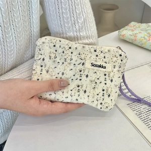 Detail of floral embroidery on cotton cosmetic pouch with lace and purple zipper strap