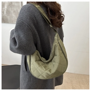 Olive green quilted nylon hobo bag shown in a stylish crossbody wear on a model coat