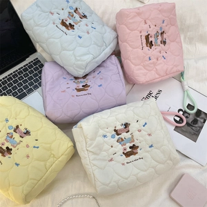 Macro shot of colorful quilted heart makeup bags featuring dog embroidery and text