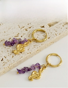 Detailed view of 18k gold note earrings with natural purple crystal beads on stone