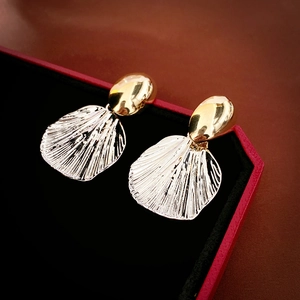 Elegant gold oval studs with silver fan-shaped shell drops on a luxury jewelry box