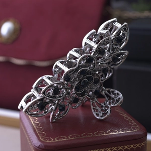 Detailed shot of retro silver flower hair claw with dark blue rhinestones on red box